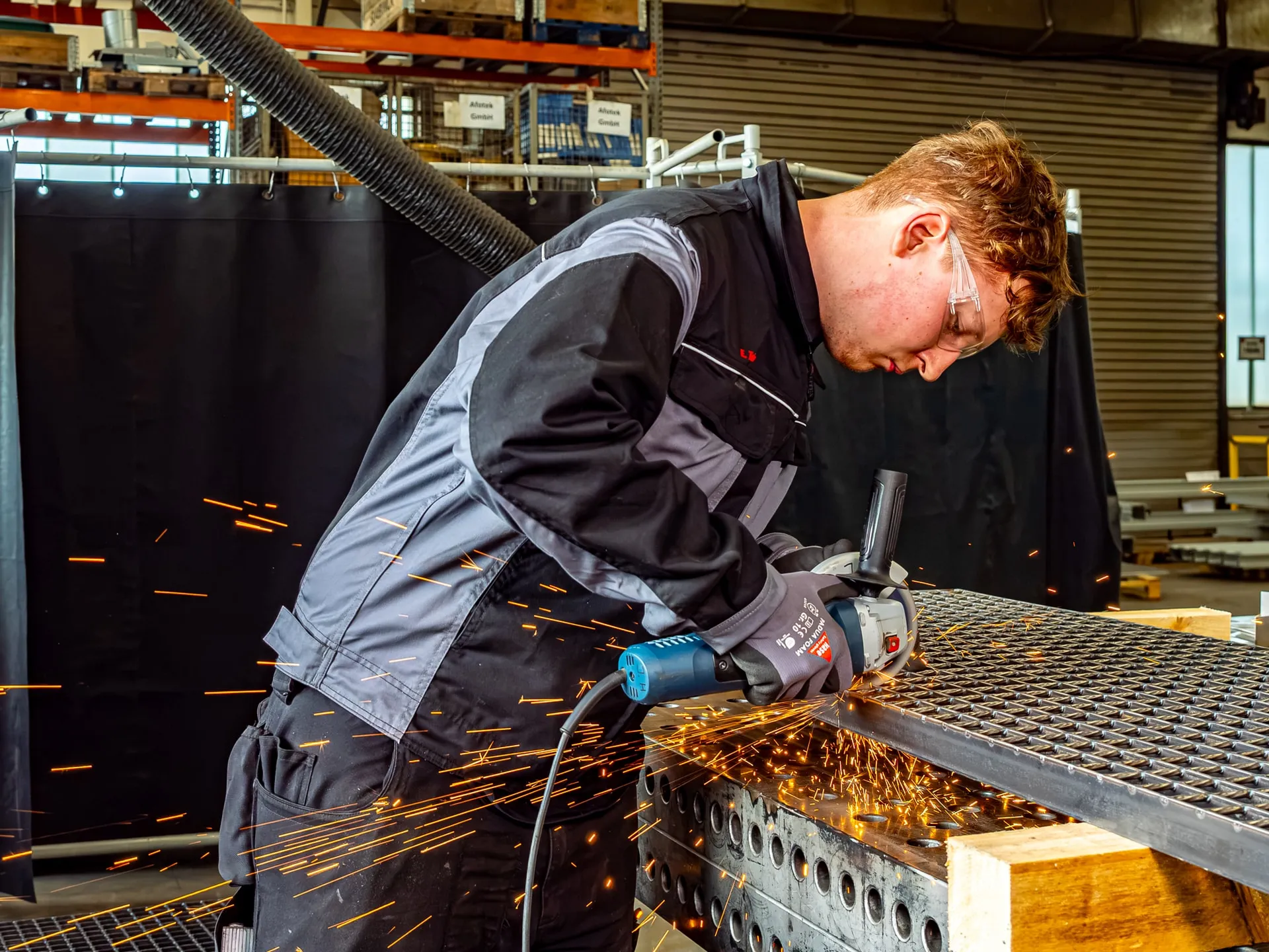 Ein Mitarbeiter bearbeitet ein Metallteil mit einem Schleifgerät