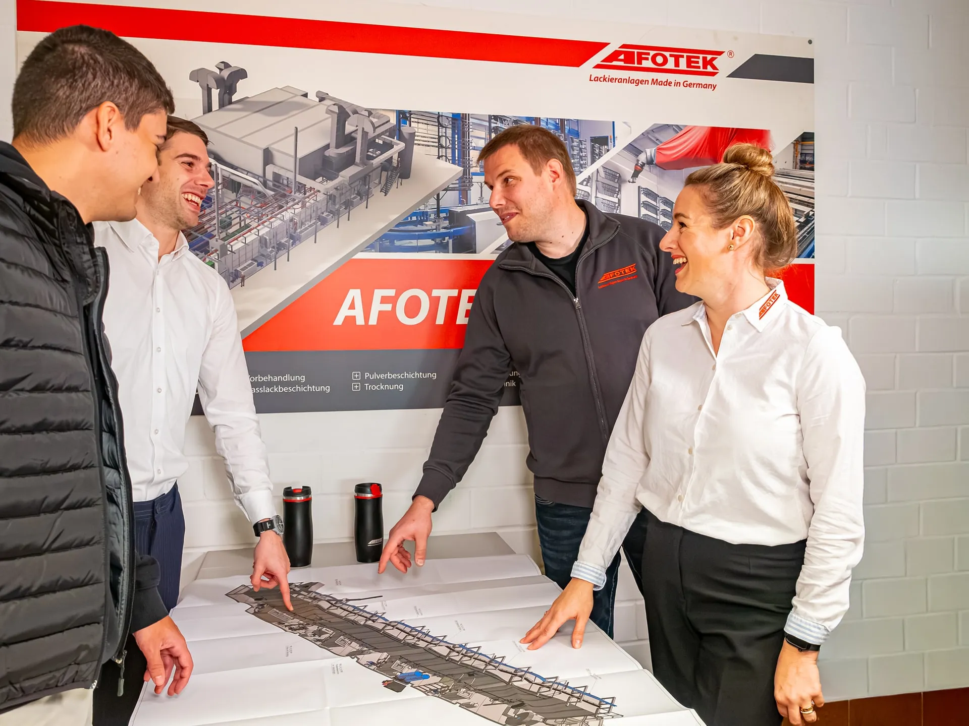 Vier Personen im gemeinsamen Gespräch an einer Anlagenzeichnung bei AFOTEK